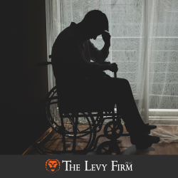 An injured person sits in a wheelchair with head in hands